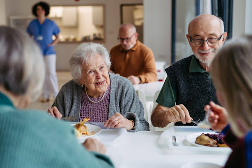 seniors sitting around the dinner table conversing and smiling